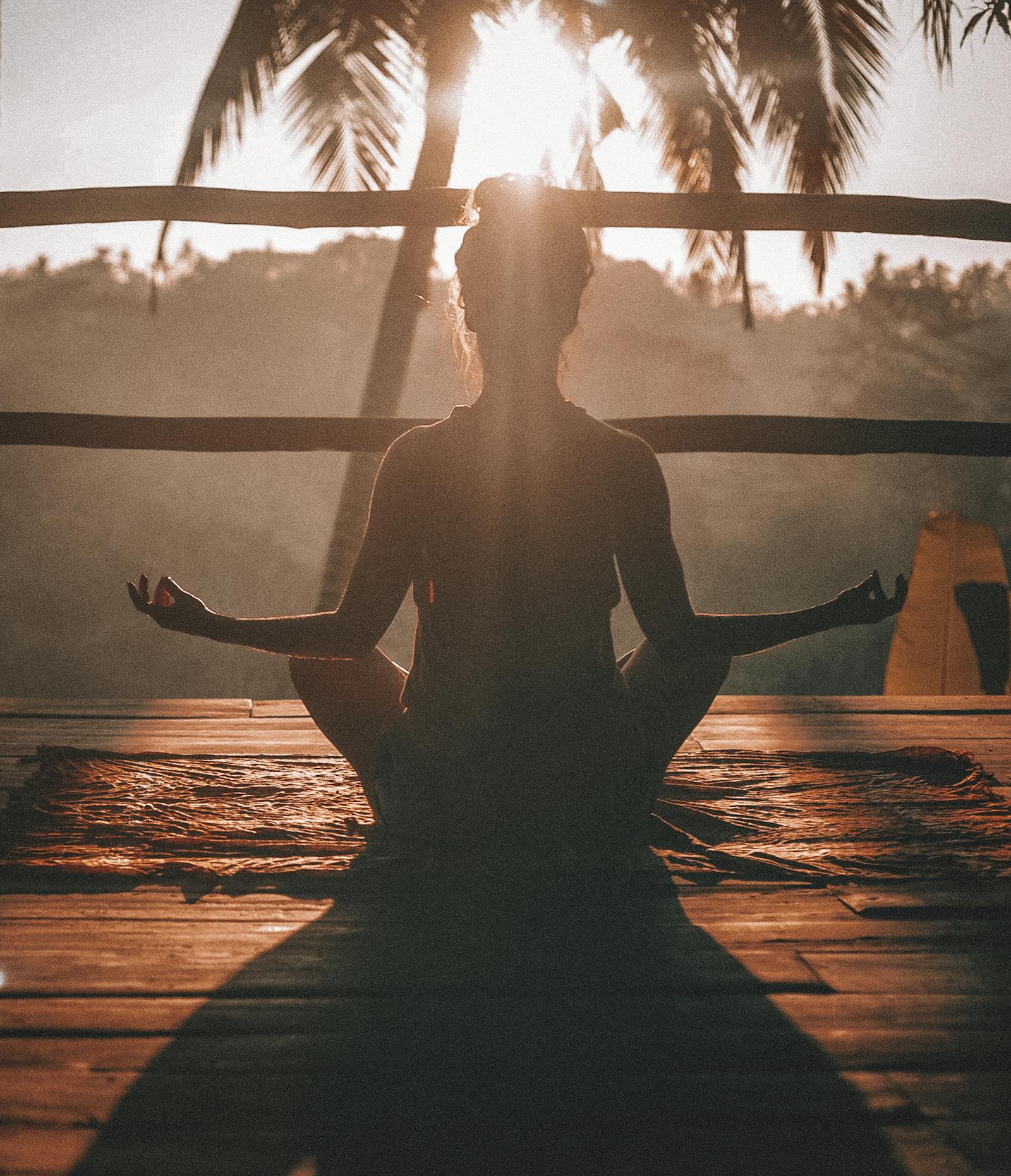 Person practicing yoga at sunrise on a mountain peak